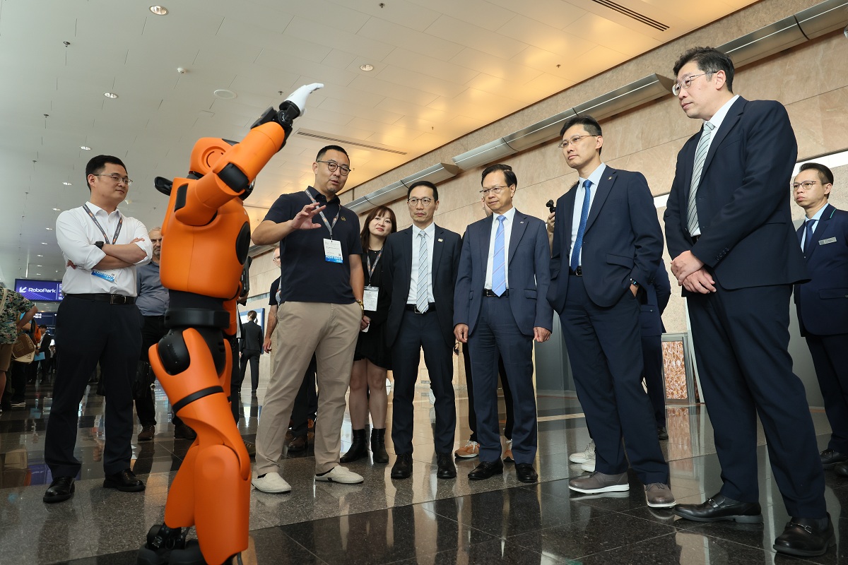 The Acting Commissioner for Digital Policy, Mr Daniel Cheung (first right), watched the robot demonstration in an exhibition booth with other guests.