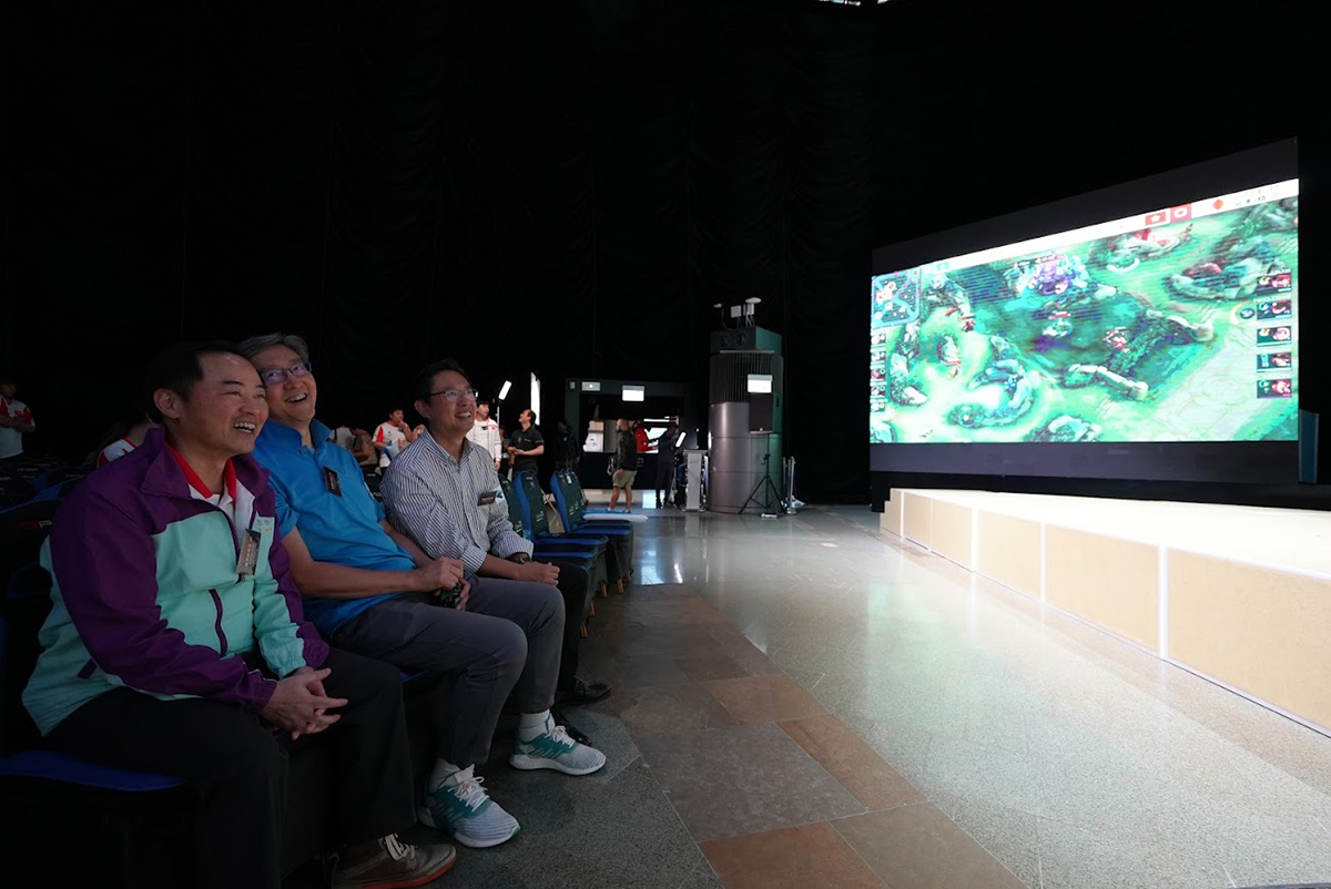 政府资讯科技总监黄志光先生（左）、香港数码港管理有限公司行政总裁任景信先生（中）及港区全国人大代表冼汉廸先生（右）于「庆祝香港回归祖国26周年暨亚运征途撑王者荣耀中国香港队直播派对」一同观看电竞赛事。