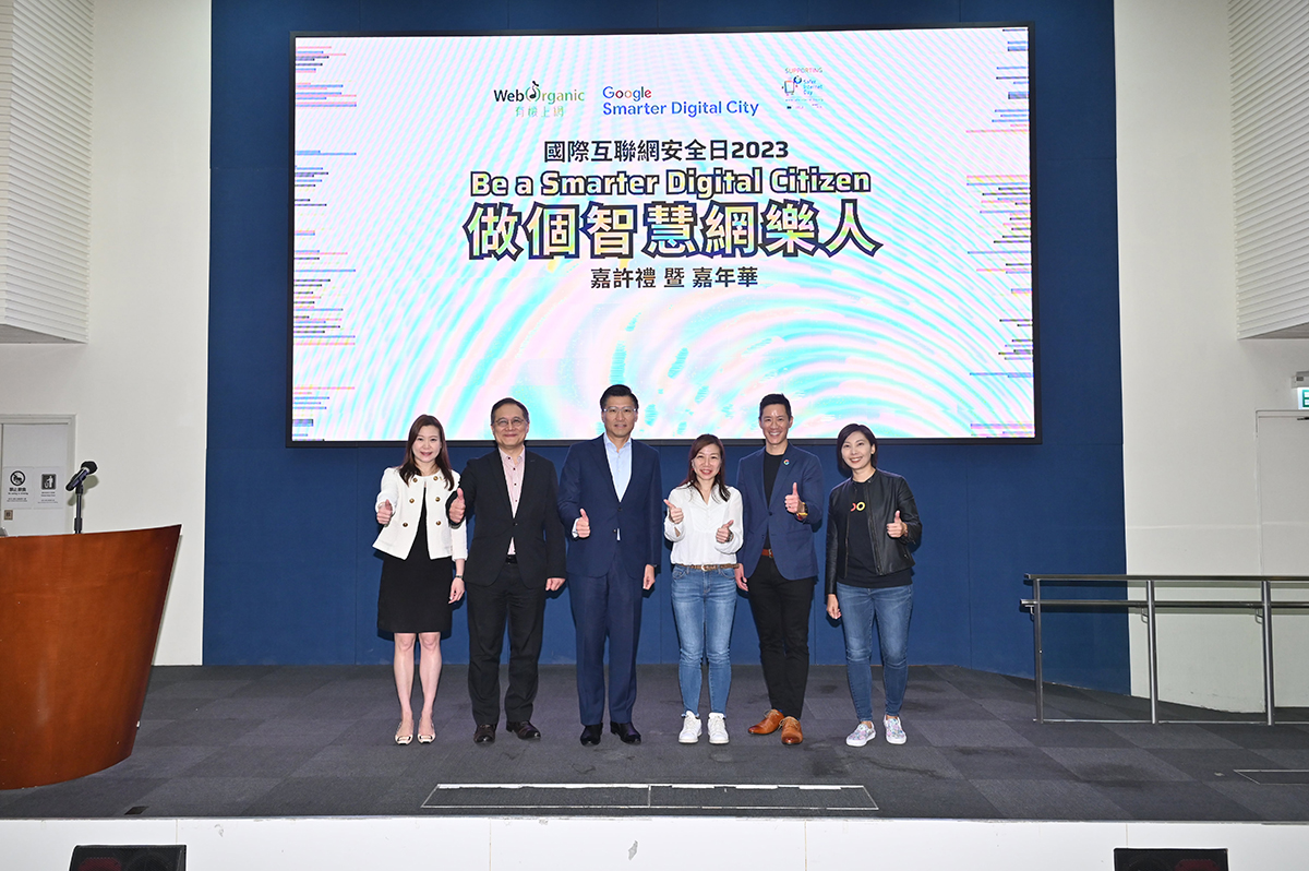 副政府資訊科技總監黃敬文先生（左二）與立法會科技創新界議員邱達根議員（左三）、香港社會服務聯會資訊科技資源中心署理總經理何美儀女士（右三）、Google 香港銷售及營運總經理余名德先生（右二）、個人資料私隱專員公署助理個人資料私隱專員（企業傳訊及合規）黎智敏女士（左一）及 Google 亞太區企業傳訊經理黃紫茵女士（右一）於「『國際互聯網安全日2023 – “做個智慧網樂人” 』 嘉許禮暨嘉年華」台上合照。